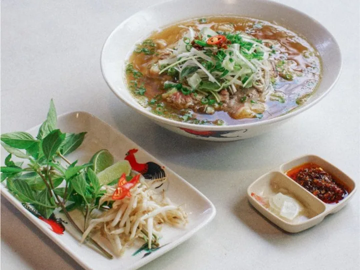 Semangkuk Mee Beras Sup Daging dengan ulam segar, taugeh dan minyak cili di tepi