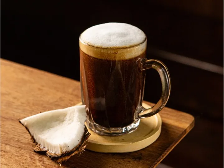 Secawan kopi panas berbuih di atas papan kayu